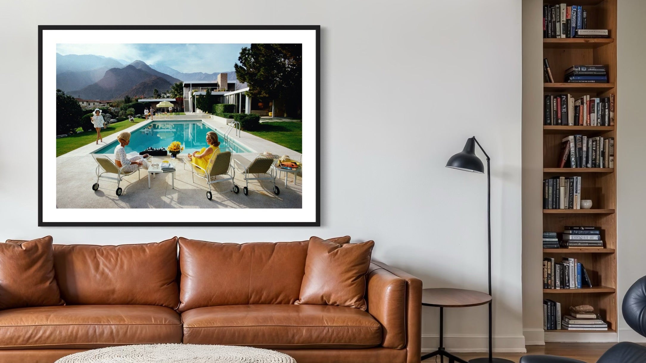 Living room with brown leather sofa, ottoman, and bookshelf.