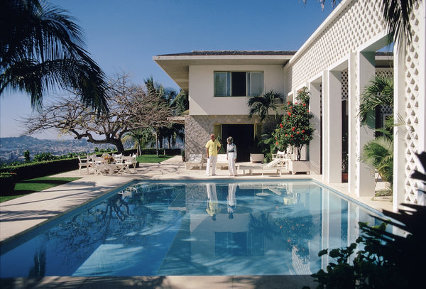 Modern house with a pool and people in the backyard.  The Picturalist Slim Aarons Collection