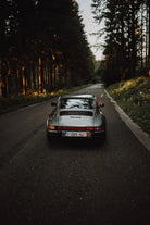 Vintage Porsche 911 Carrera driving on a forest road photographed from behind by Alex Meunier for The Picturalist