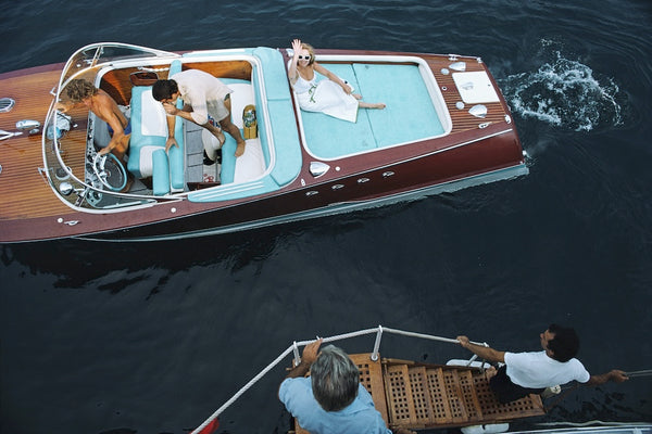 Vintage-style boat with people on a body of water.  The Picturalist Wall Art and Photography for Designed Interiors. Slim Aarons Collection, Sailing. Riva Boat . Getty Images Gallery.