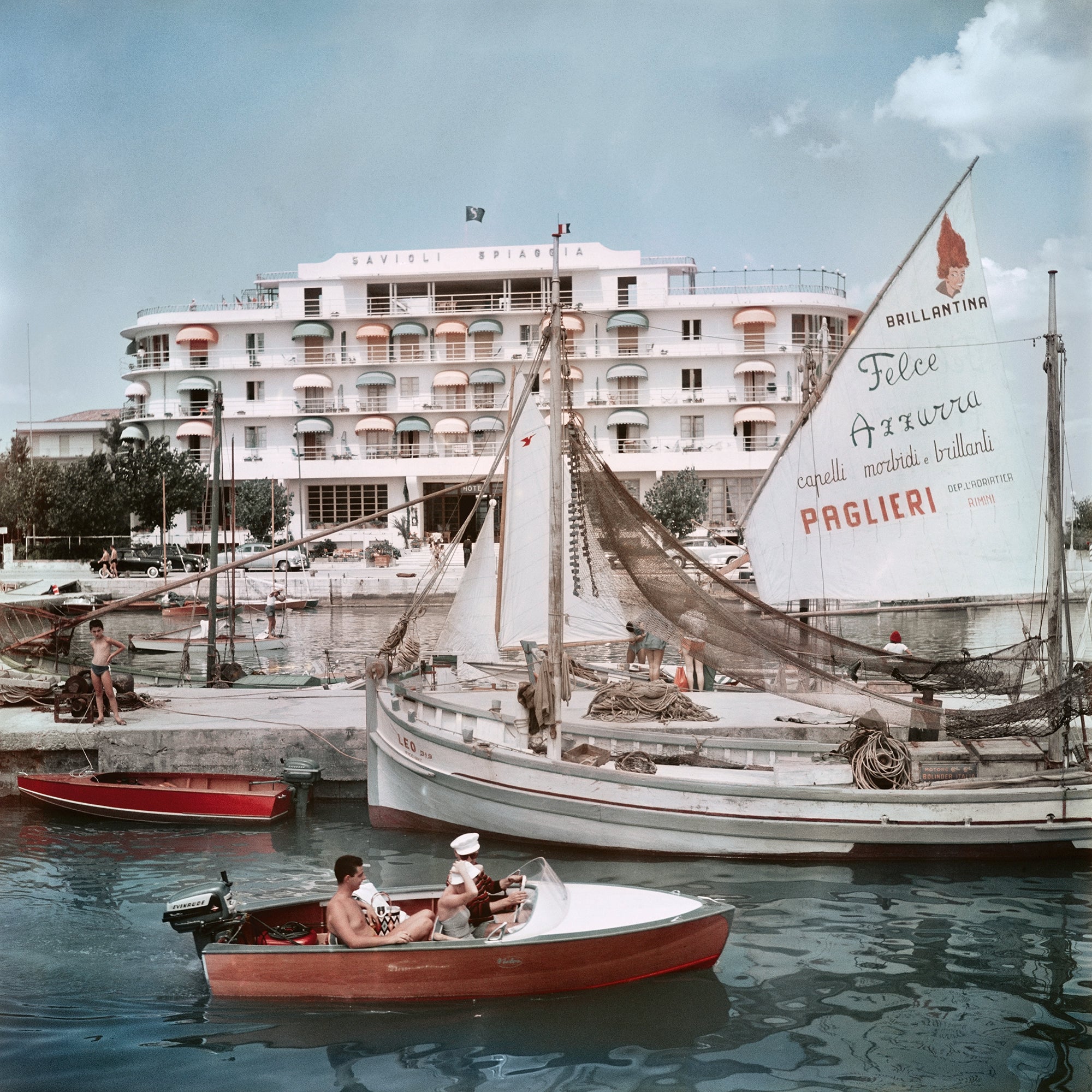 Savioli Spiaggia Hotel, Riccione by Slim Aarons, Getty Images asset 1496421414, featuring boats in the harbour beside the Savioli Spiaggia Hotel in Riccione, Italy, available from The Picturalist as fine art prints USA and framed prints Canada for luxury coastal interiors and hospitality design projects.