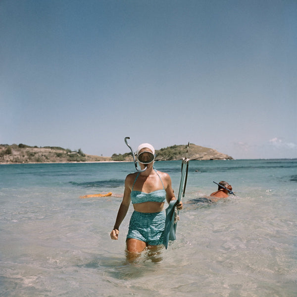 Snorkeling in Antigua by Slim Aarons, Getty Images asset 2208106024, featuring a stylish woman emerging from crystal-clear Caribbean waters with snorkeling gear, available from The Picturalist as fine art prints USA and framed prints Canada for luxury coastal interiors, hospitality projects, and designer-grade wall decor.