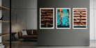 A three-panel framed wall art set hangs on a dark gray wall in a modern living room. The artwork depicts sunbathing figures on wooden decks and a swimmer in bright blue water, each panel in a white frame.