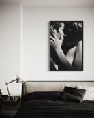 Black and white photograph of a couple embracing on a wall above a bed.