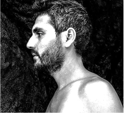 Black and white profile of a person with a beard against a dark background