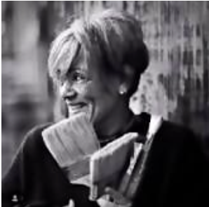 Black and white photo of a woman holding paint brushes outdoors