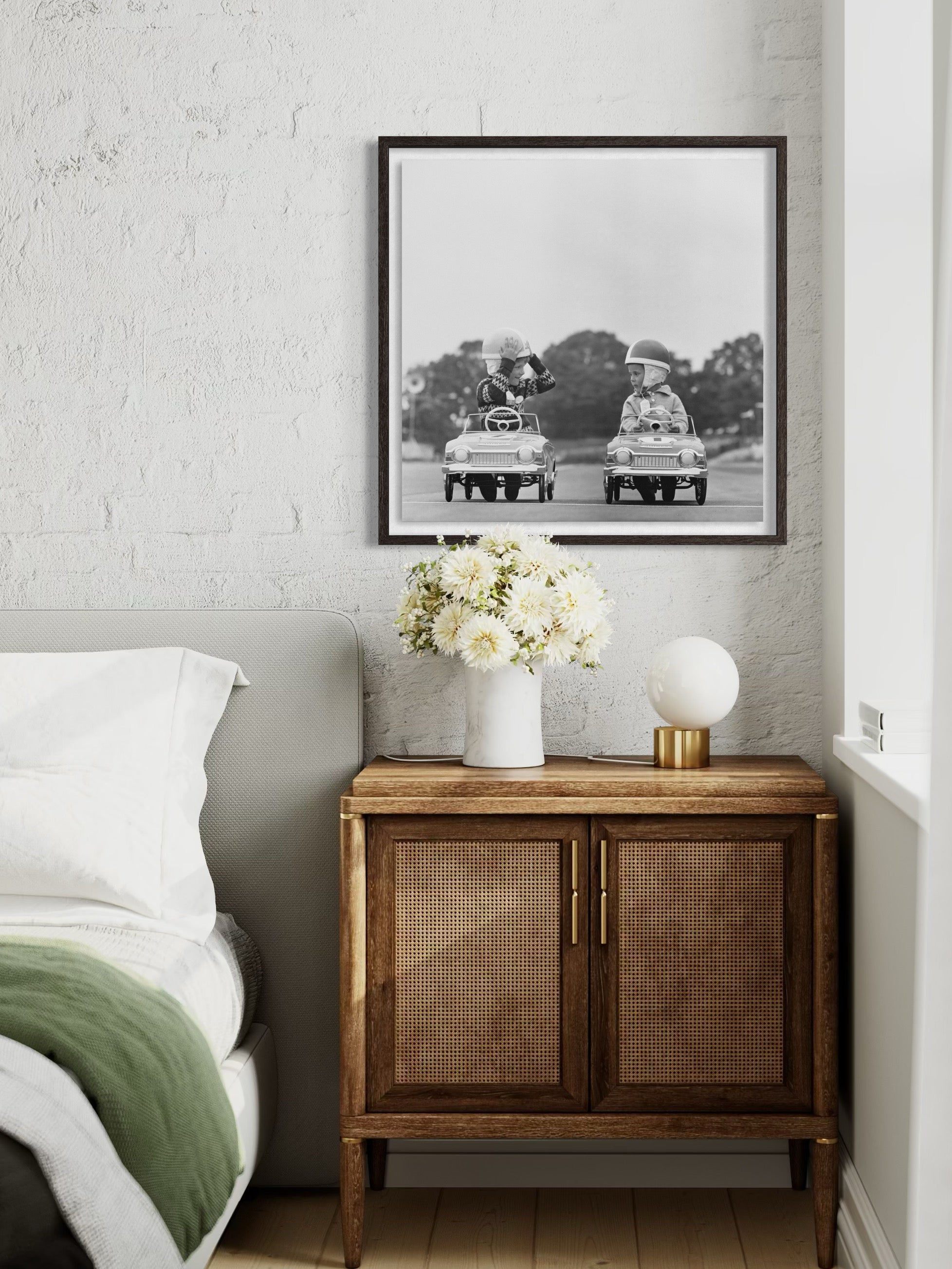 Framed black and white photograph on a wall above a wooden cabinet with decorative items.