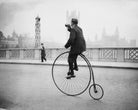 Penny Farthing Bugle by Fox Photos, vintage black-and-white photograph of a cyclist on a penny-farthing with a bugle, licensed through Getty Images and framed by The Picturalist.