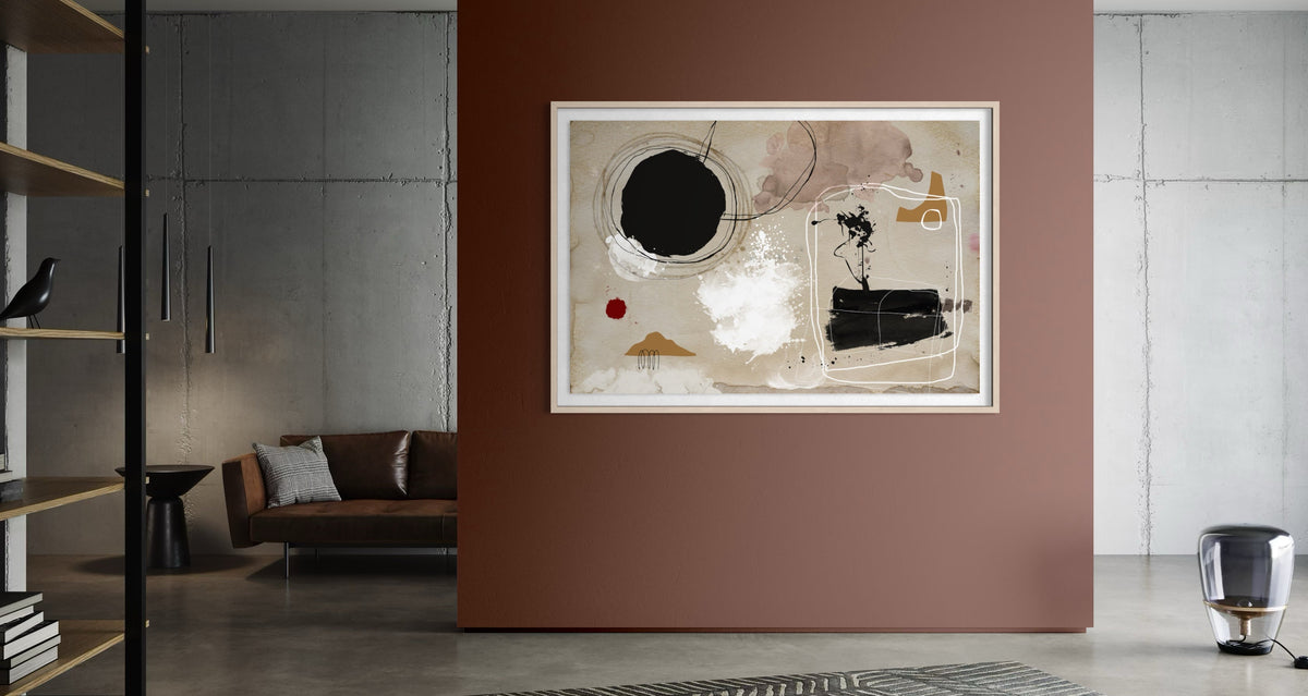 An abstract framed wall art print hangs on a terracotta-colored accent wall in a modern living room setting with concrete floors, a sofa, and shelving. The Picturalist Wall Art and Photography for Designed Interiors.