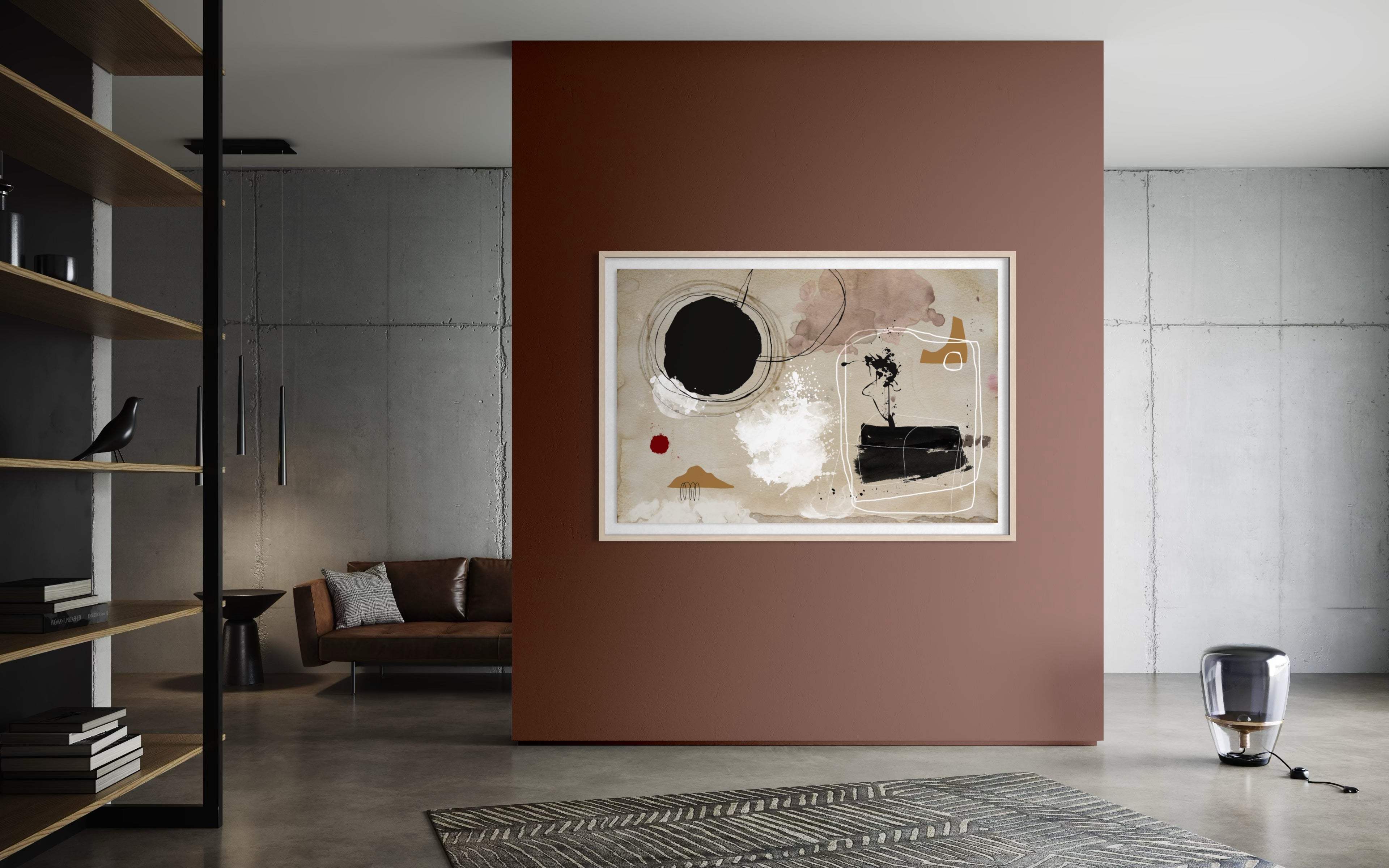 An abstract framed wall art print hangs on a terracotta-colored accent wall in a modern living room setting with concrete floors, a sofa, and shelving. The Picturalist Wall Art and Photography for Designed Interiors.