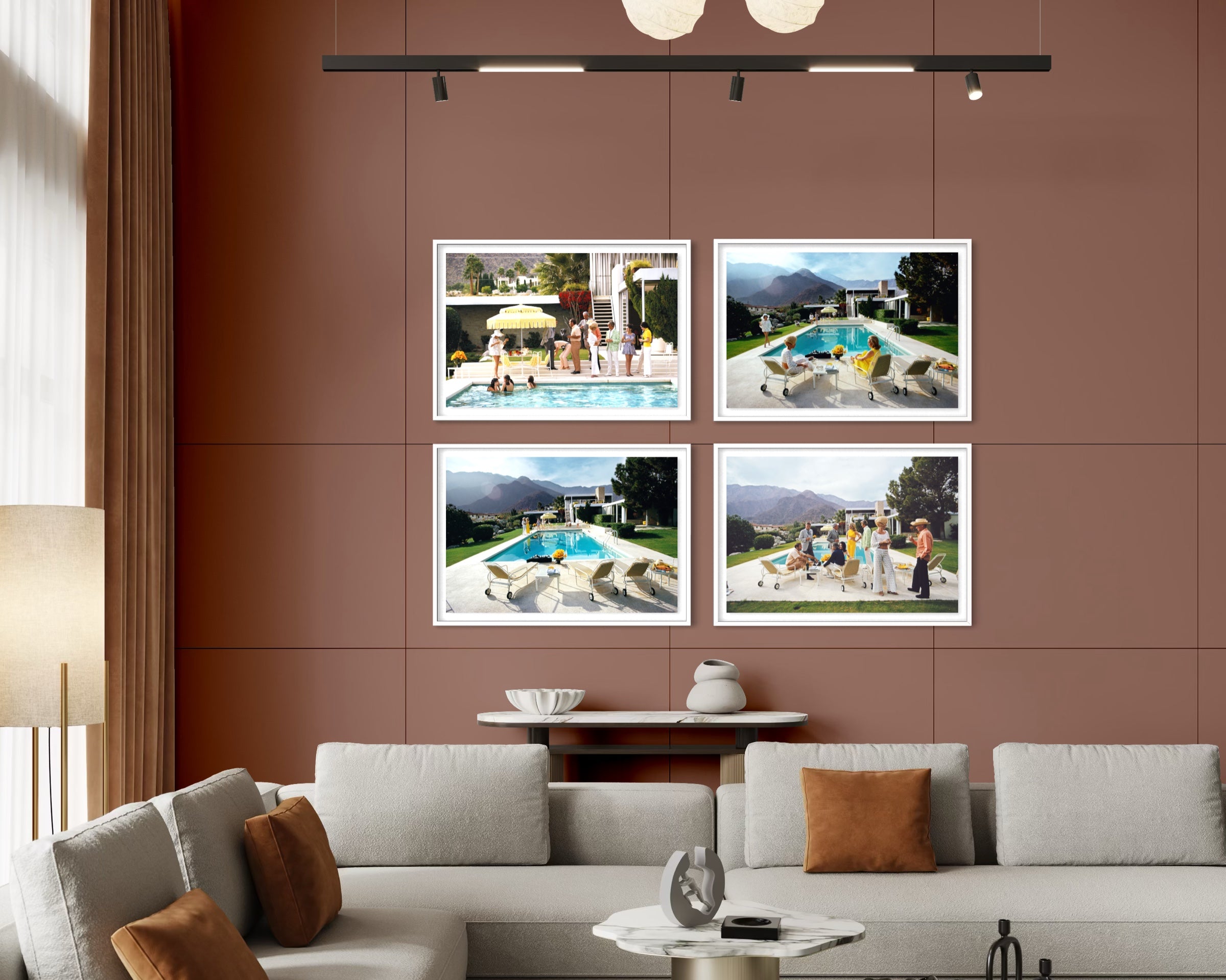 A modern living room setting featuring a wall-mounted four-panel framed print set. The prints showcase scenic poolside and mountain views, styled on a terracotta-colored wall above a light gray sectional sofa. The Picturalist Wall Art and Photography for Designed Interiors. Slim Aarons Collection, Poolside. Getty Images Gallery. 