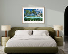 A framed tropical beach print with palm trees, a swimming pool, and blue sky, displayed on a light gray wall above a modern bed in a styled bedroom. The Picturalist Wall Art and Photography for Designed Interiors. Slim Aarons Collection, Poolside. Getty Images Gallery. 