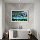 A framed wall art print depicting a tropical beach resort pool scene with palm trees, blue sky, and white umbrellas, displayed above a freestanding white bathtub in a modern bathroom. The Picturalist Wall Art and Photography for Designed Interiors. Slim Aarons Collection, Poolside. Getty Images Gallery. 