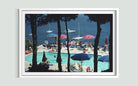 A framed art print depicting a scenic poolside view with sailboats on the blue sea, framed by dark pine tree silhouettes, and presented on a light gray wall.
