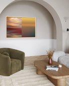 A framed abstract wall art print hangs in a modern living room with a green armchair, wooden coffee table, and neutral walls.