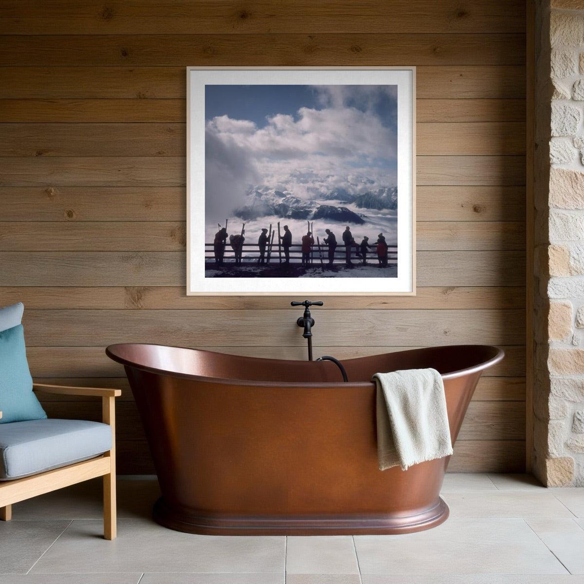A framed square art print depicting a dramatic cloudy sky and silhouetted figures over water, displayed on a wood-paneled wall above a copper freestanding bathtub in a bathroom setting.