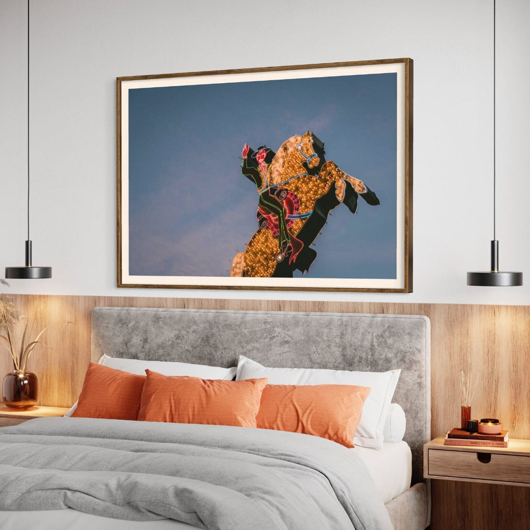 Luminous Cowboy Tale neon cowboy artwork shown above a contemporary bed setting, framed by The Picturalist