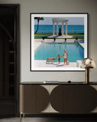Framed photograph of a pool scene with people and a dog, displayed on a wall above a cabinet.