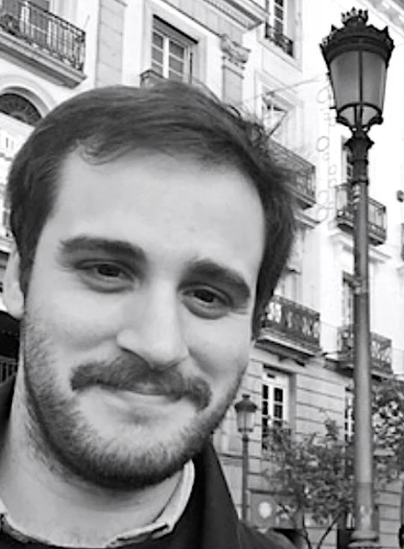 Black and white photo of a man with a beard in an urban setting