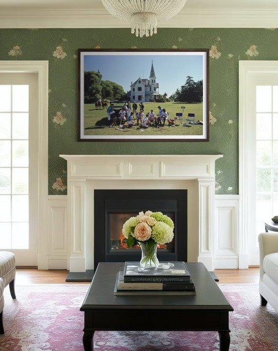 Living room with a fireplace, floral arrangement, and framed picture of a group on grass.