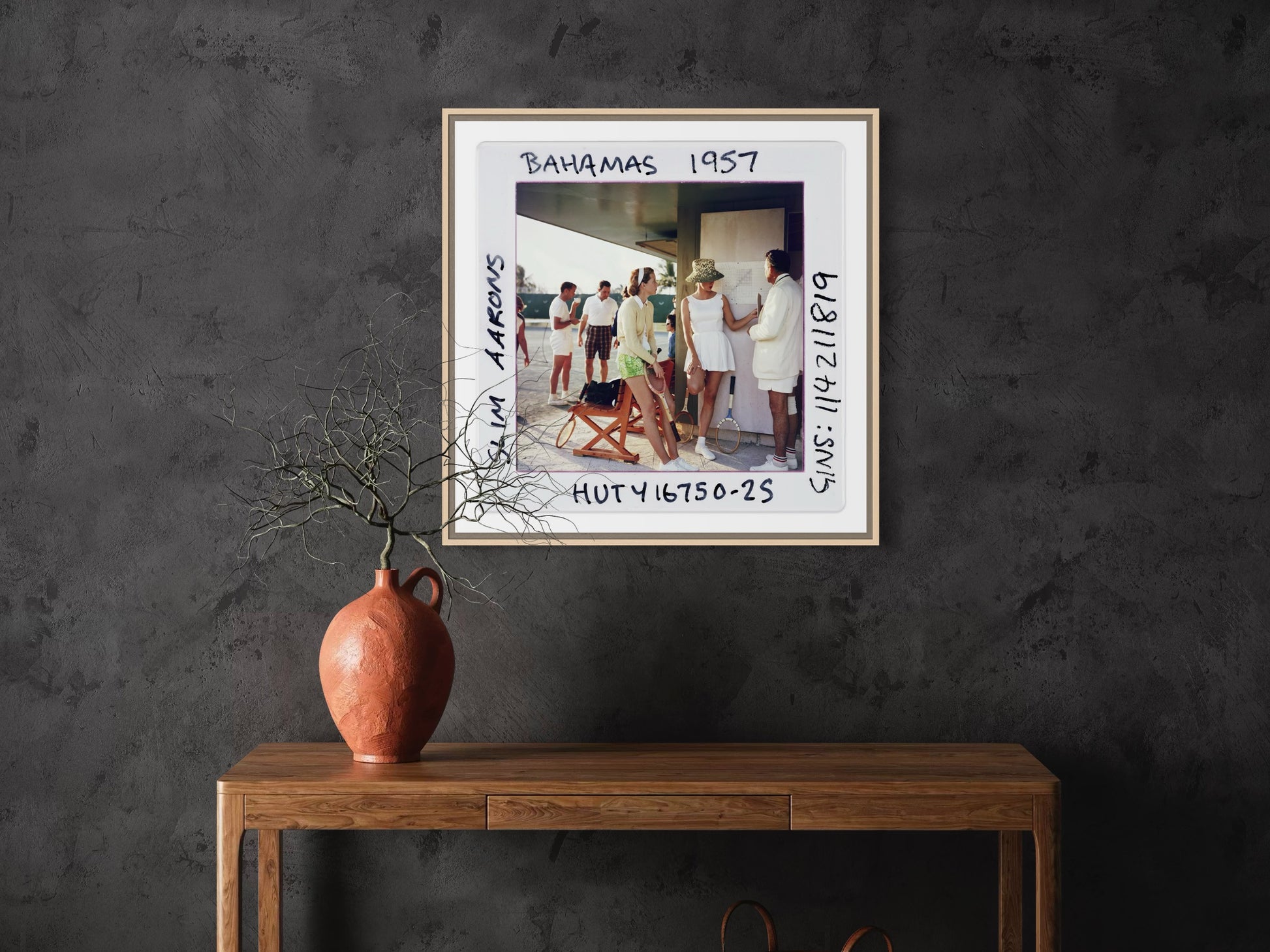 Framed photograph on a dark wall above a wooden console table with a vase.