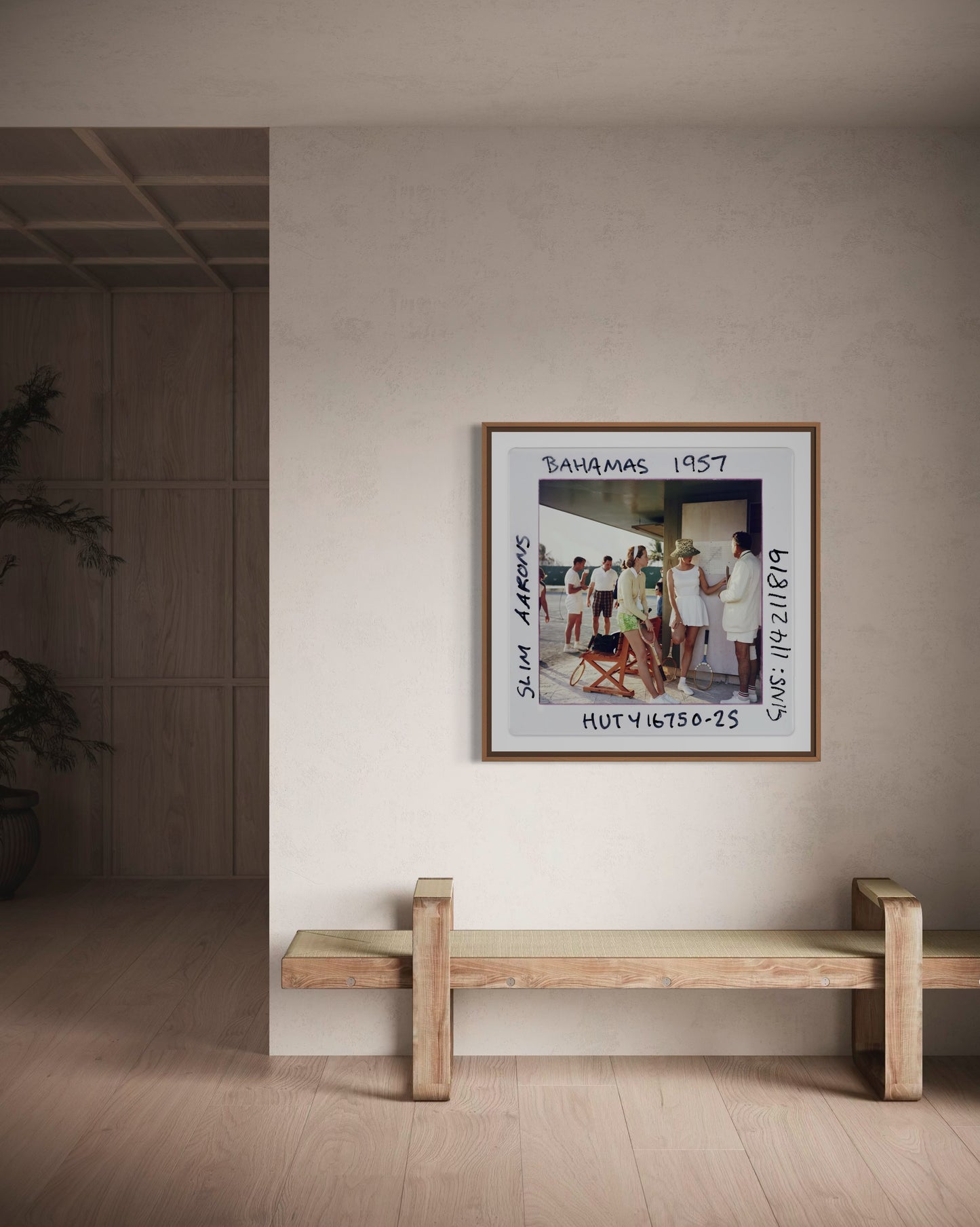 Framed artwork on a wall above a wooden bench in a minimalistic room.