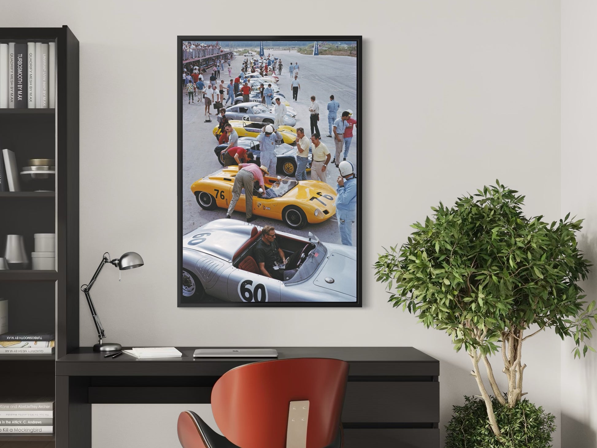 Framed artwork of a race car scene on a wall above a desk with a plant and lamp.