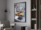 Framed artwork of a race car scene on a wall in a room with furniture.