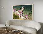 Framed photograph of a beach scene with people and umbrellas hanging on a wall above a sofa.