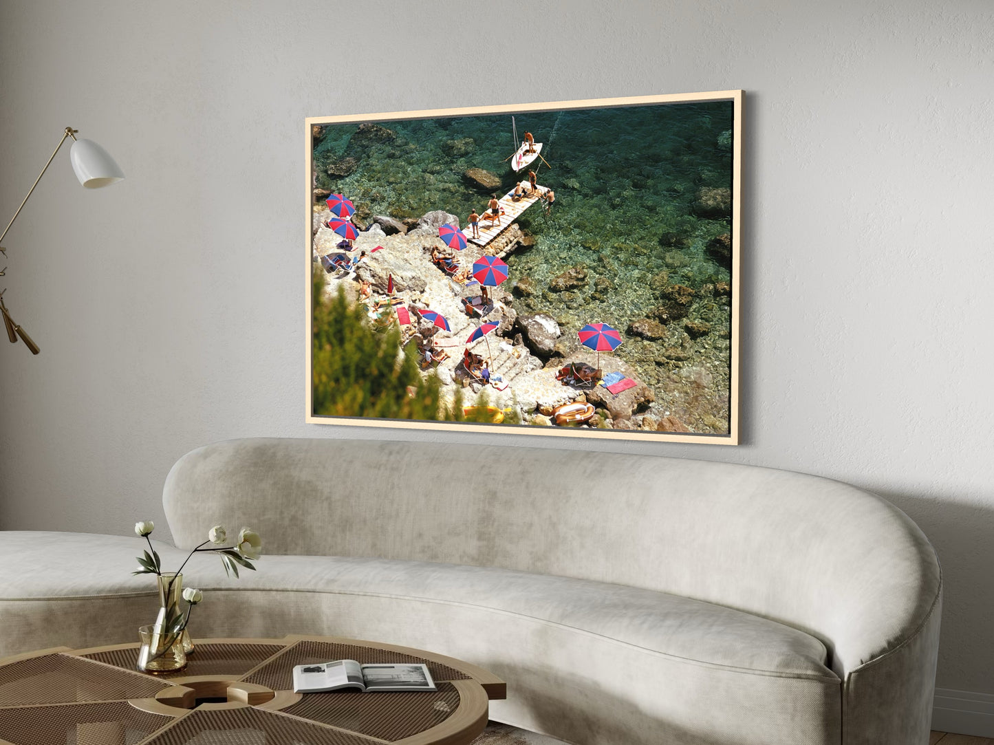 Framed photograph of a beach scene with people and umbrellas hanging on a wall above a sofa.