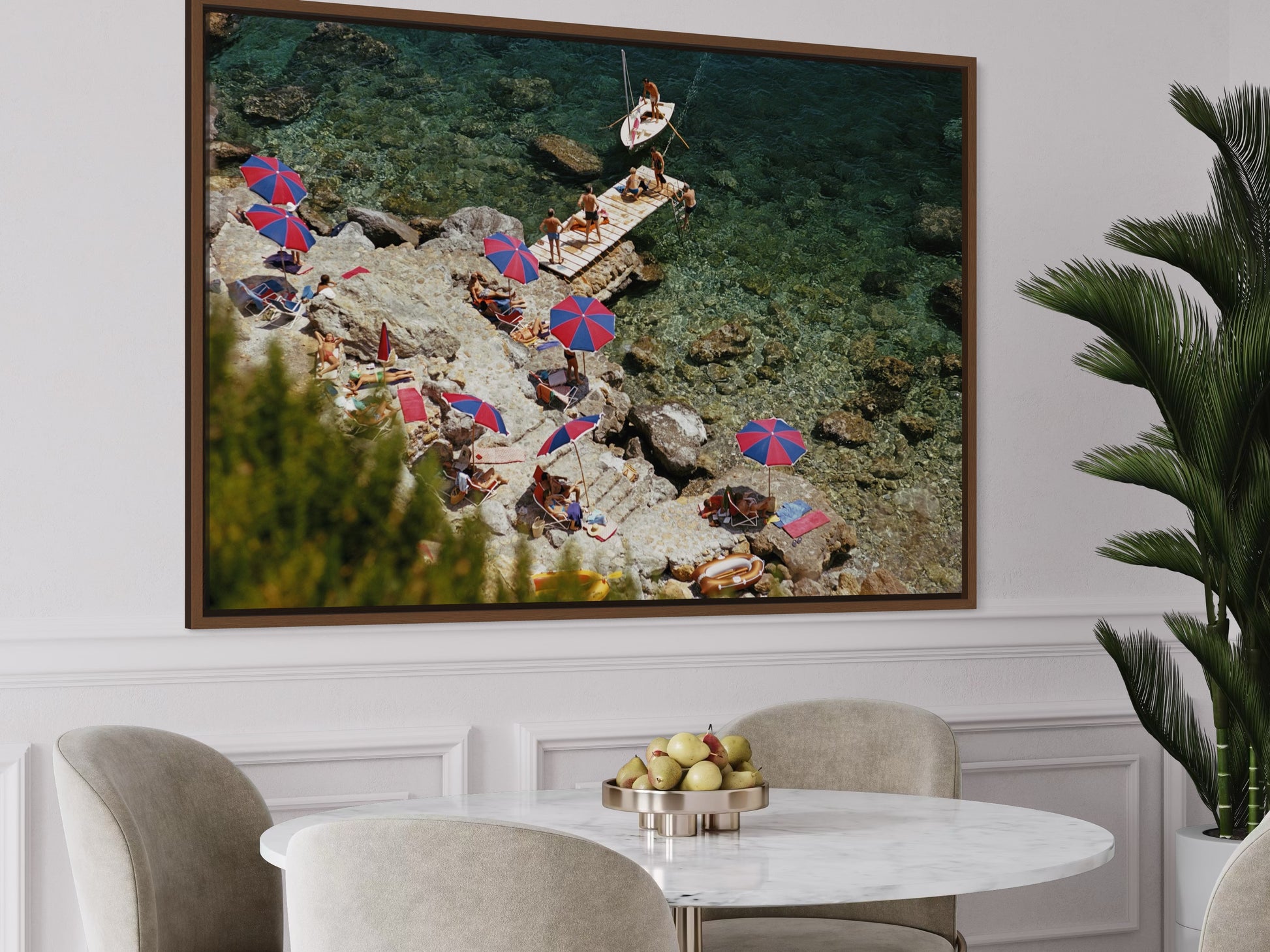 Framed artwork of a beach scene with people and umbrellas above a dining table.
