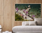 Framed artwork of a beach scene with people and umbrellas on a wooden wall above a sofa.