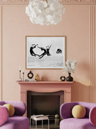 Living room with pink walls, purple furniture, and a framed black and white artwork above a fireplace.