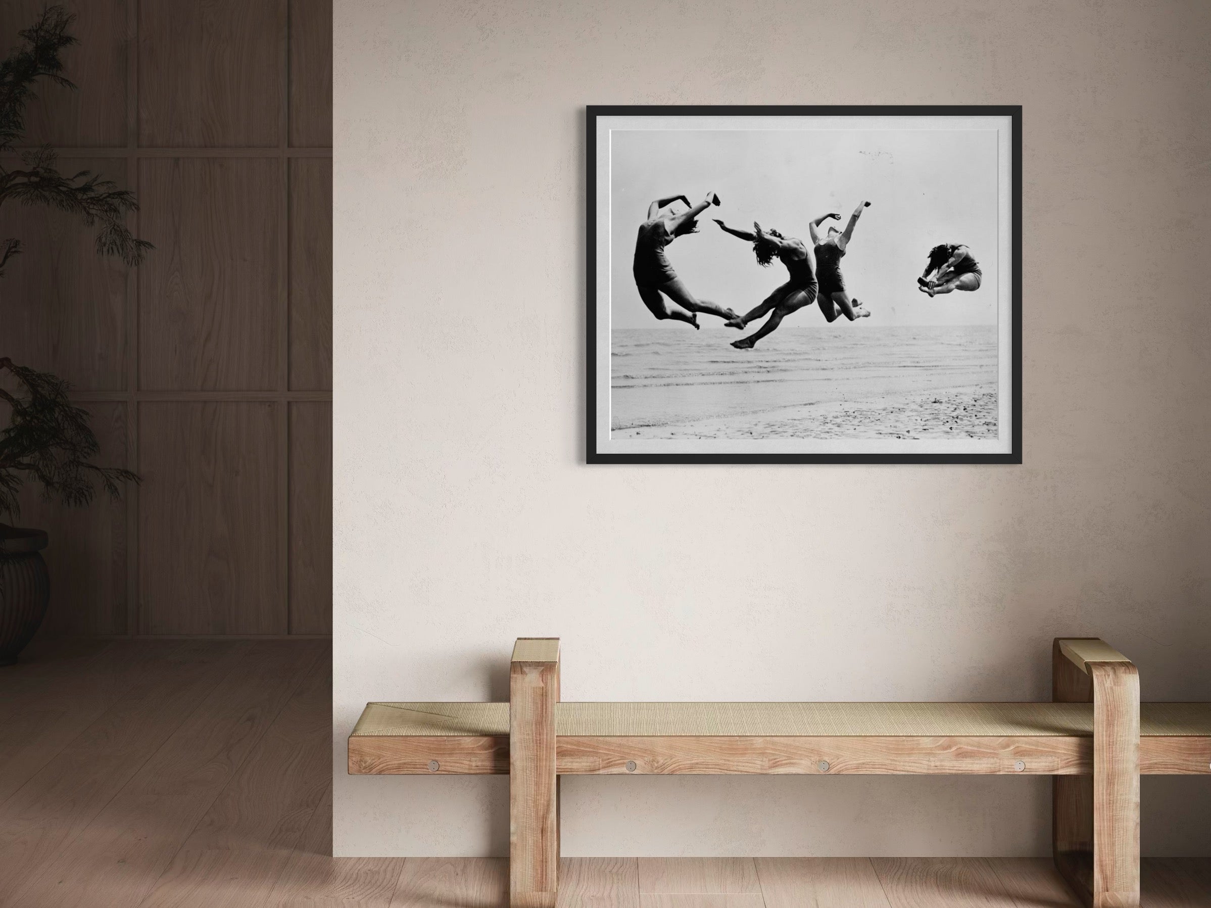 Framed black and white photograph of children playing on a beach above a wooden bench.