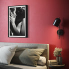 Bedroom with red wall, framed artwork, and wall sconce.