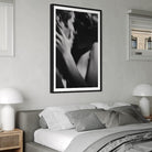 Framed black and white artwork above a bed in a bedroom setting