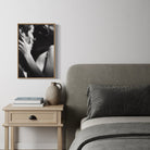 Bedroom with gray upholstered bed and wooden side table, featuring a framed black and white photograph on the wall.
