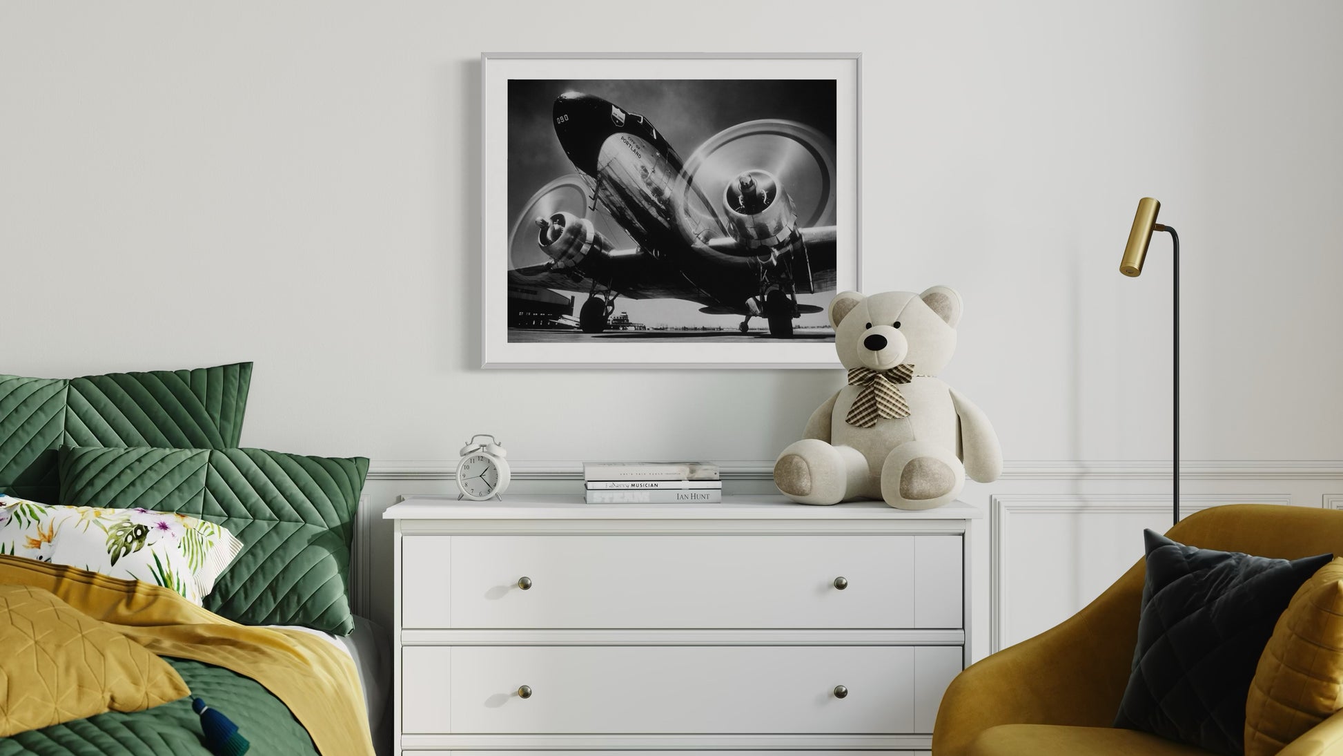 Children's room with green bed, white dresser, teddy bear, and framed picture on wall.