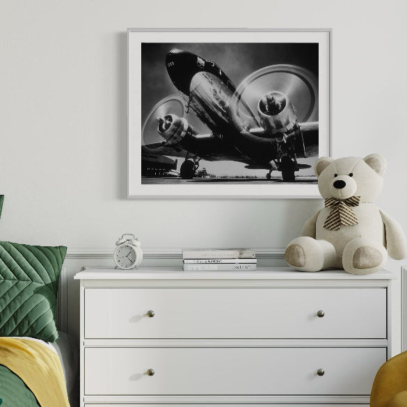 Children's room with green bed, white dresser, teddy bear, and framed picture on wall.