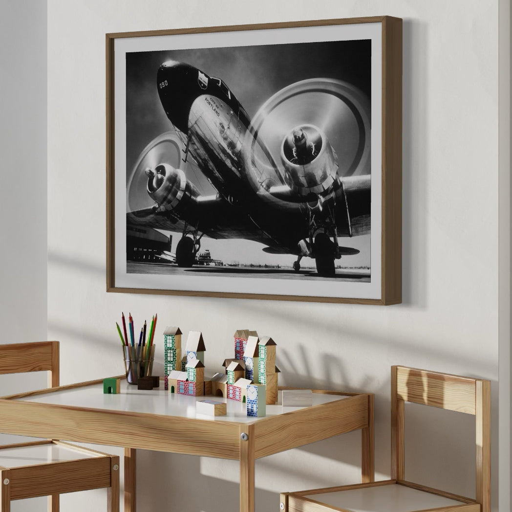 Framed black and white airplane photograph above a wooden table with stationery items.