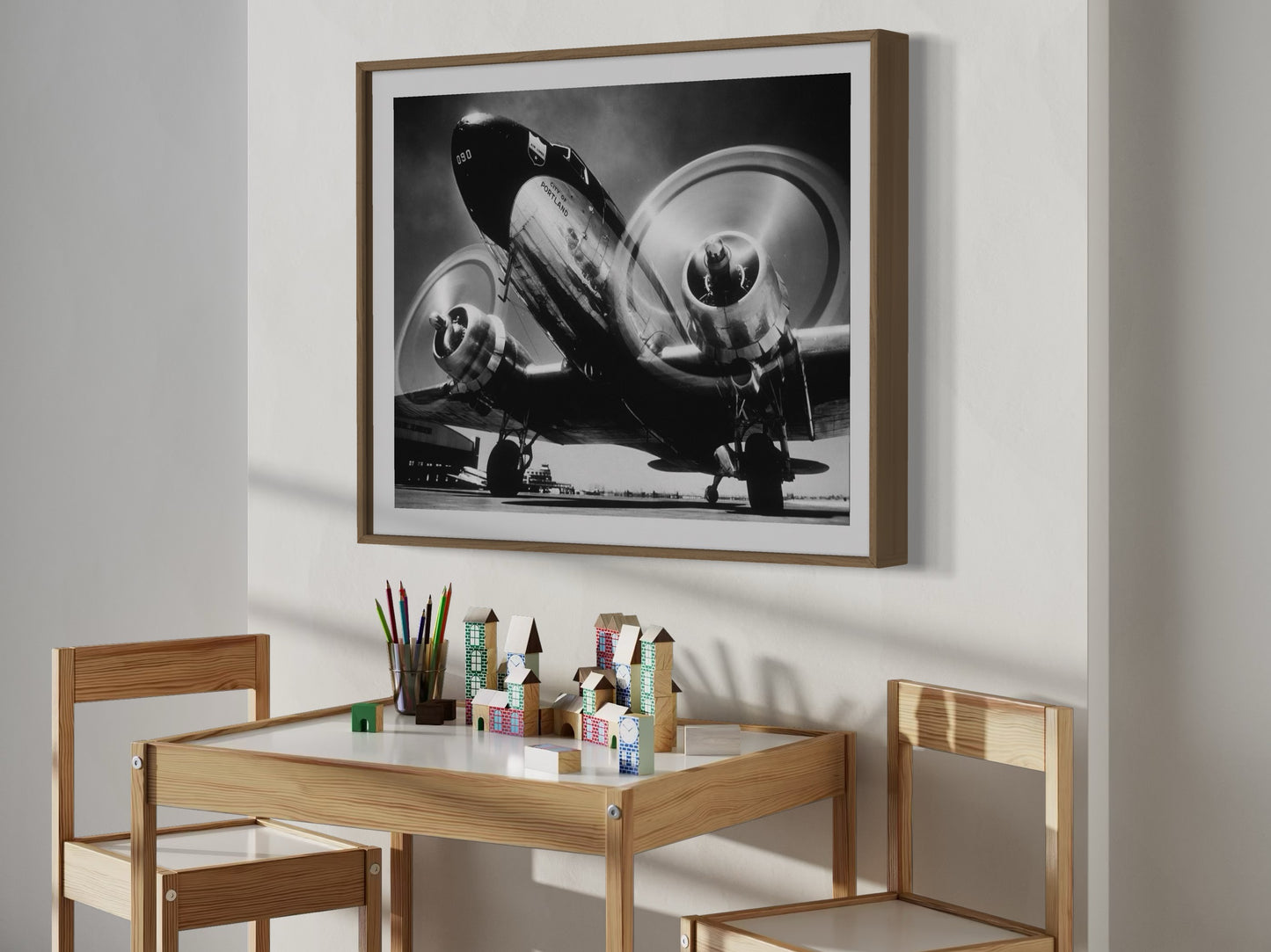 Framed black and white airplane photograph above a wooden table with stationery items.