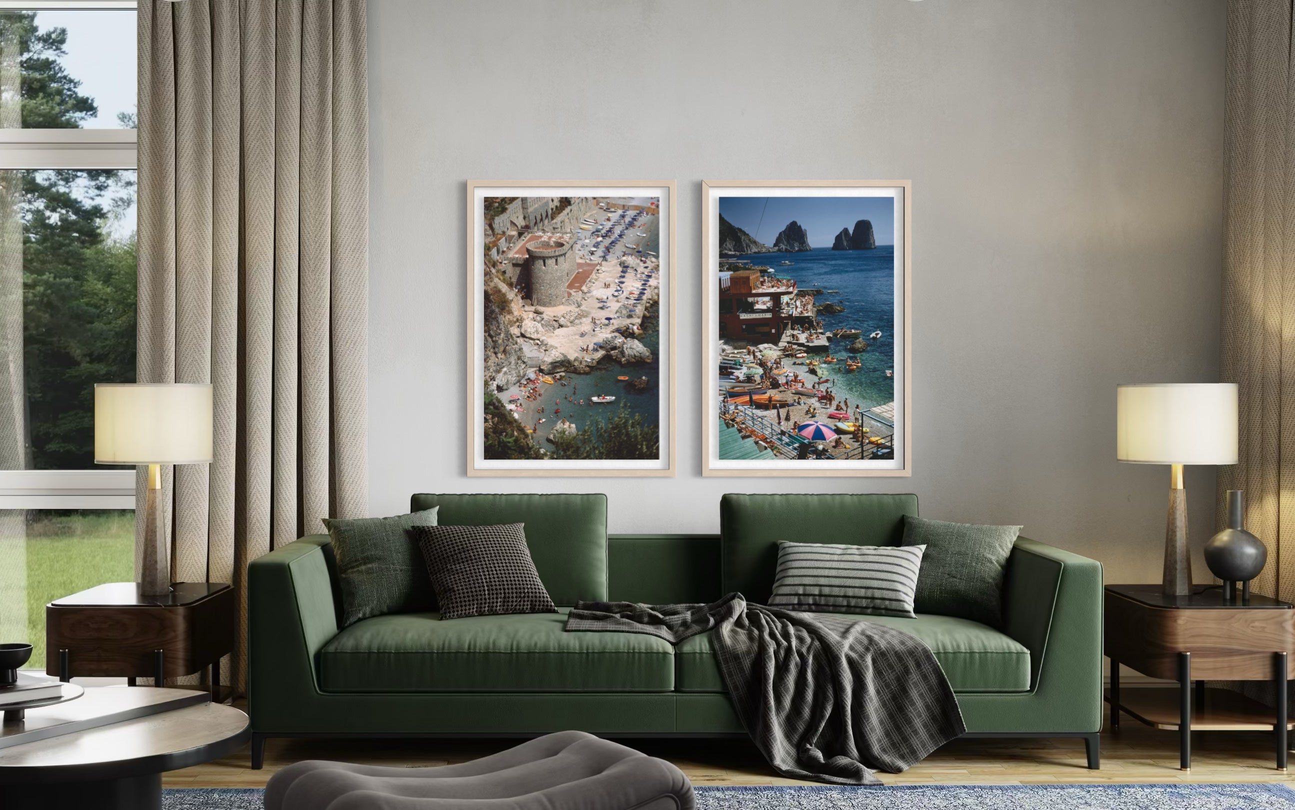 A styled living room featuring two vertical framed art prints depicting coastal town scenes, mounted on a gray wall above a green sofa with pillows and a throw blanket.