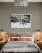 A framed art print depicting a snowy mountain scene with skiers, displayed on a gray wall above a bed in a modern bedroom setting. The Picturalist Wall Art and Photography for Designed Interiors. Slim Aarons Collection, Skiing. Getty Images Gallery. 