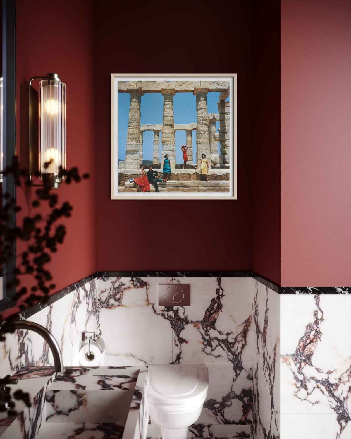 A framed art print depicting ancient stone columns and figures under a blue sky, displayed on a dark red wall in a modern bathroom with marble walls and a white toilet.