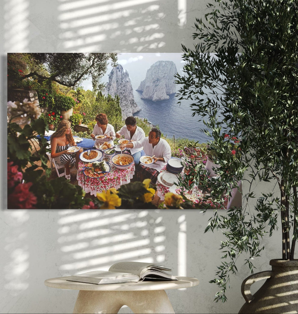 Canvas print of a group of people at a picnic with a scenic background, hanging on a wall with a plant in the foreground.