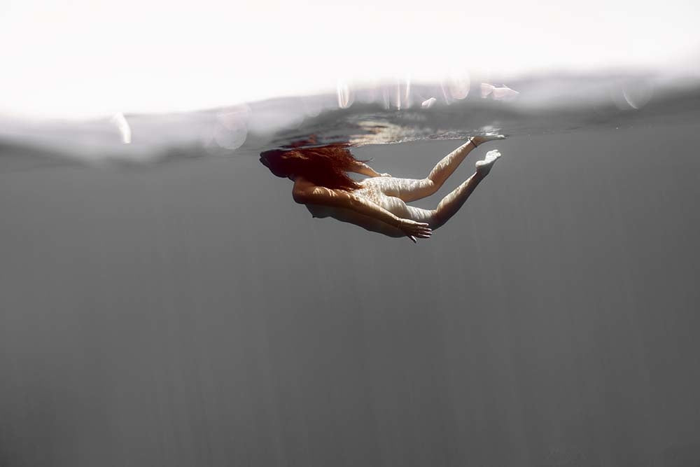 woman underwater with reflection, minimal color palette