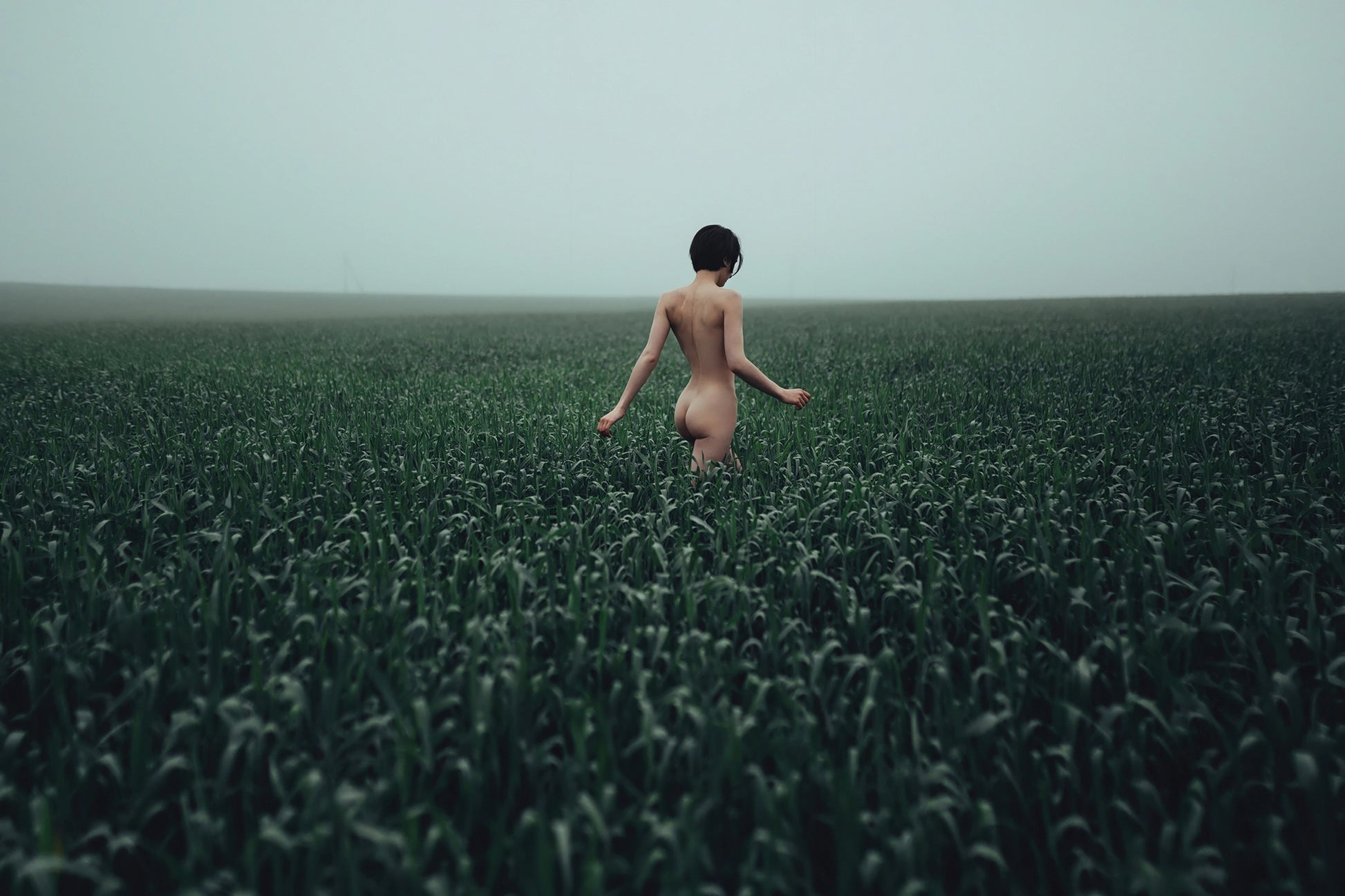 Walking in a Meadow by Igor Ustynsky — fine art photograph of a figure walking through a green field