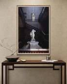 Framed artwork of a classical statue on a wall above a console table with decorative items.