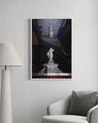 Framed artwork of a classical statue in a room with a lamp and chair.