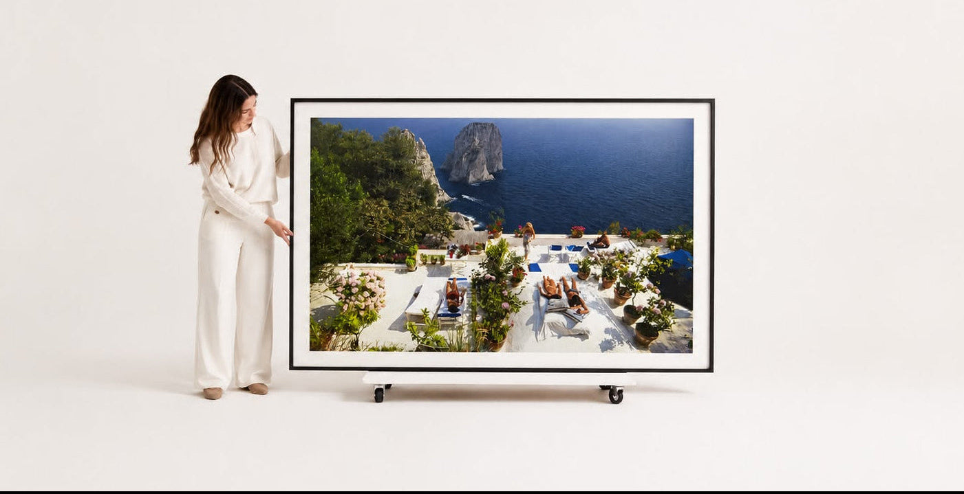 woman showcasing her large the picturalist framed slim aarons photograph of Il Canille in Capri, Italy